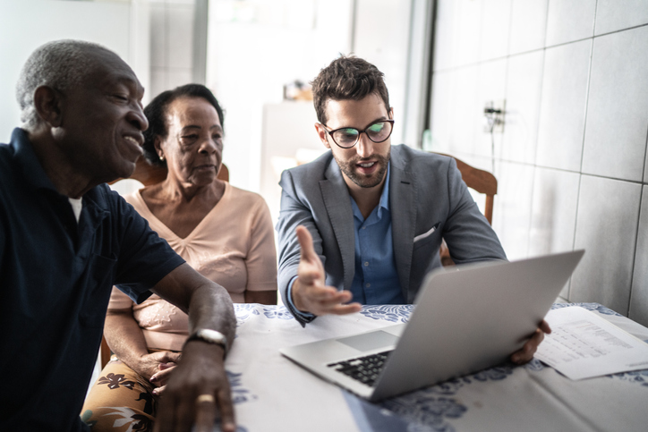 A senior couple meeting with a financial advisor to discuss the benefits and drawbacks of a 401(k) rollover.